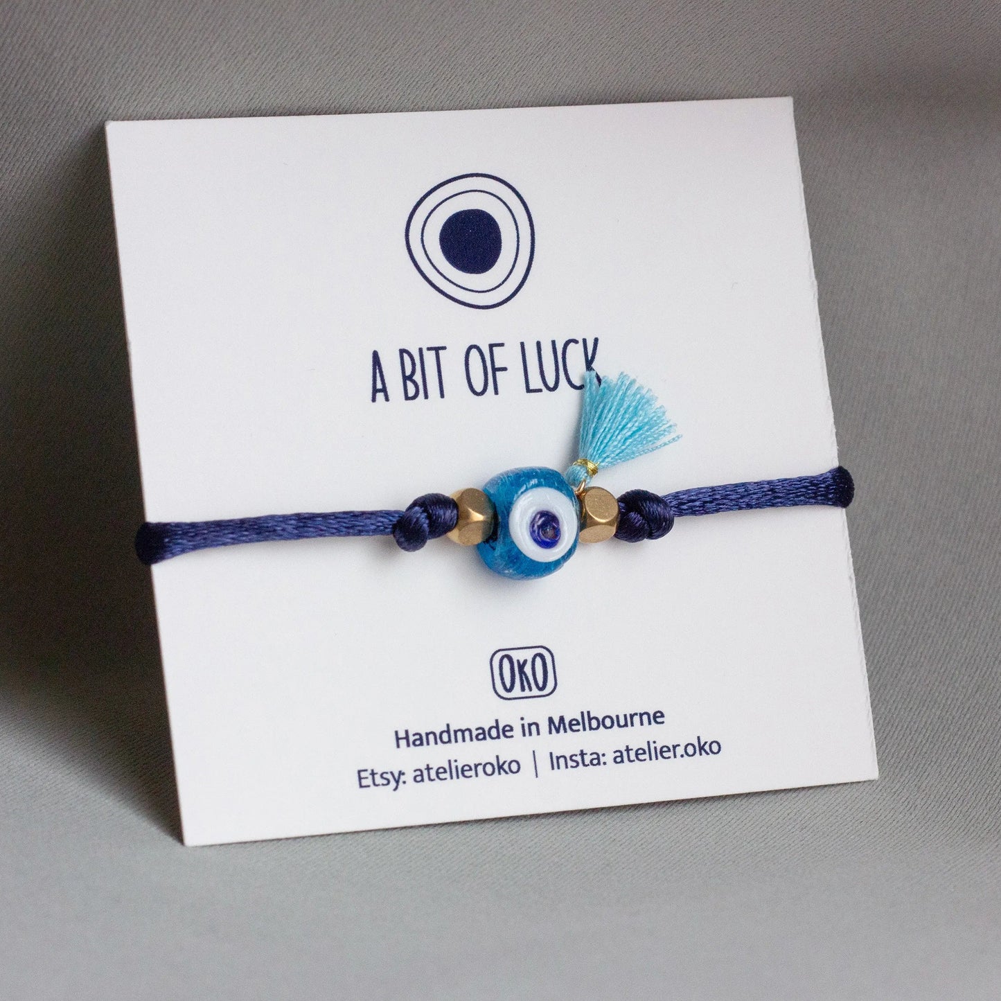 Blue bracelet with evil eye charm on a white card with 'A Bit of Luck'