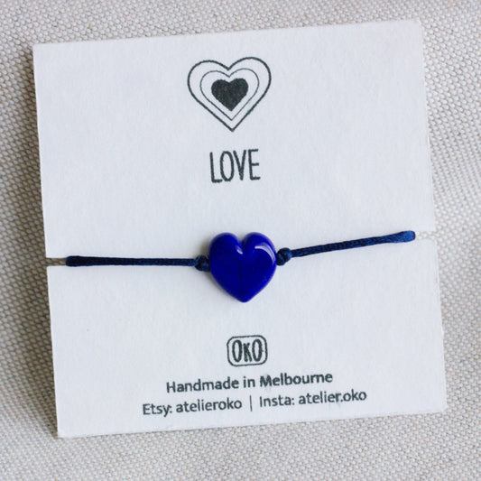 Blue heart-shaped bracelet on a white card with 'LOVE' 